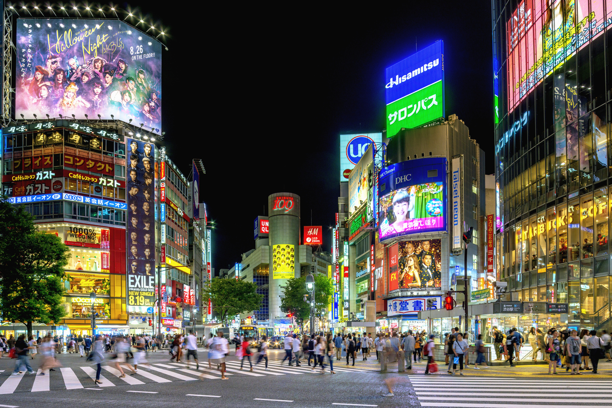 人们在夜晚穿过东京著名的涩谷十字路口。