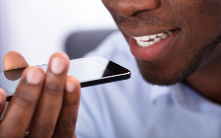 一个非洲男人使用手机语音助手的特写