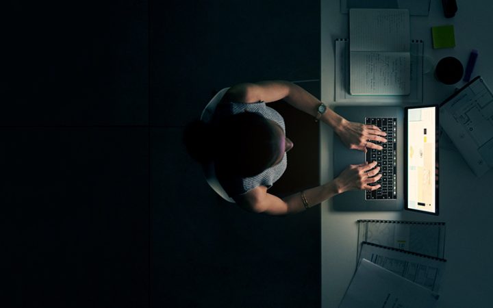一个年轻的女商人深夜在一个现代化的办公室里使用笔记本电脑的高角度镜头